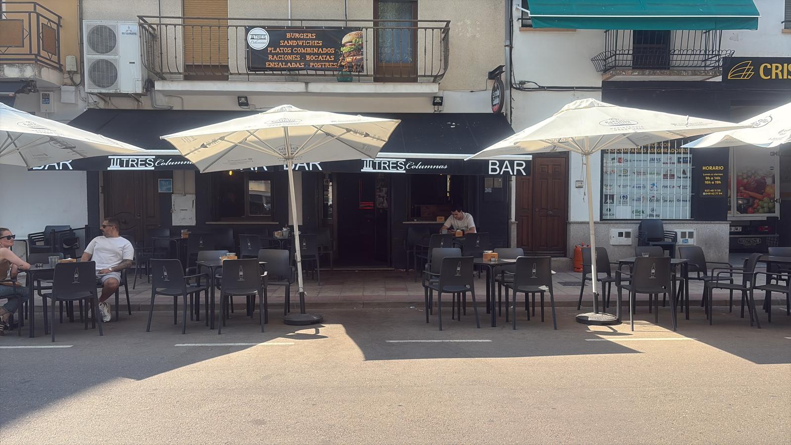 Terraza con sombrillas y clientes disfrutando en Bar Tres Columnas